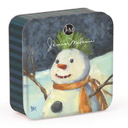 A square tin gift box with rounded corners, featuring a painted winter scene of a snowman on the front. The tin has a dark blue-gray top and side, with a striped dark blue-gray and black left edge, and a snowy white-and-blue ground with an orange scarf and green hat.