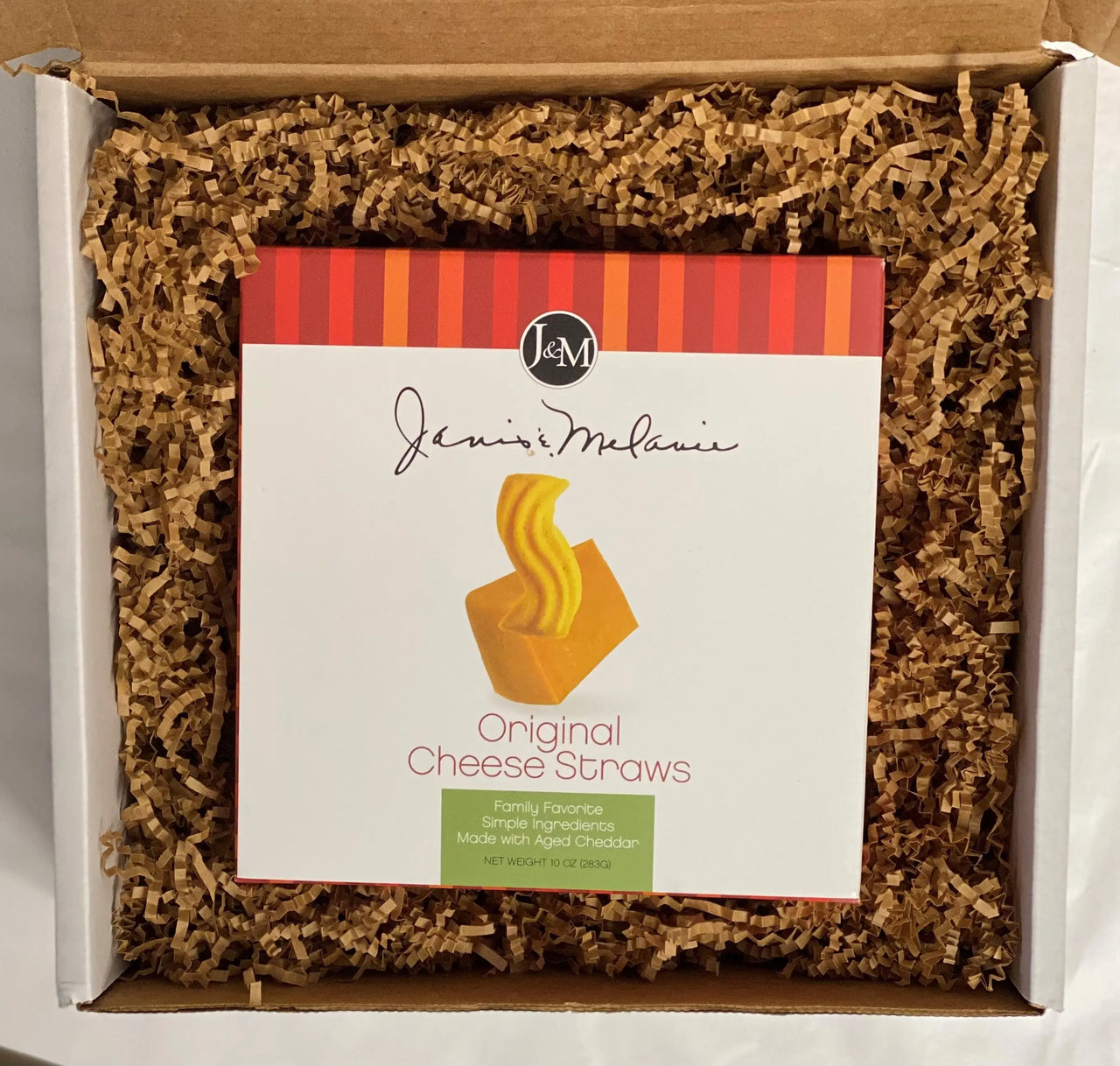 A box of Janis and Melanie Original Cheese Straws, with the product visible inside a Small Food=Love gift box, cushioned with kraft krinkle paper packaging.