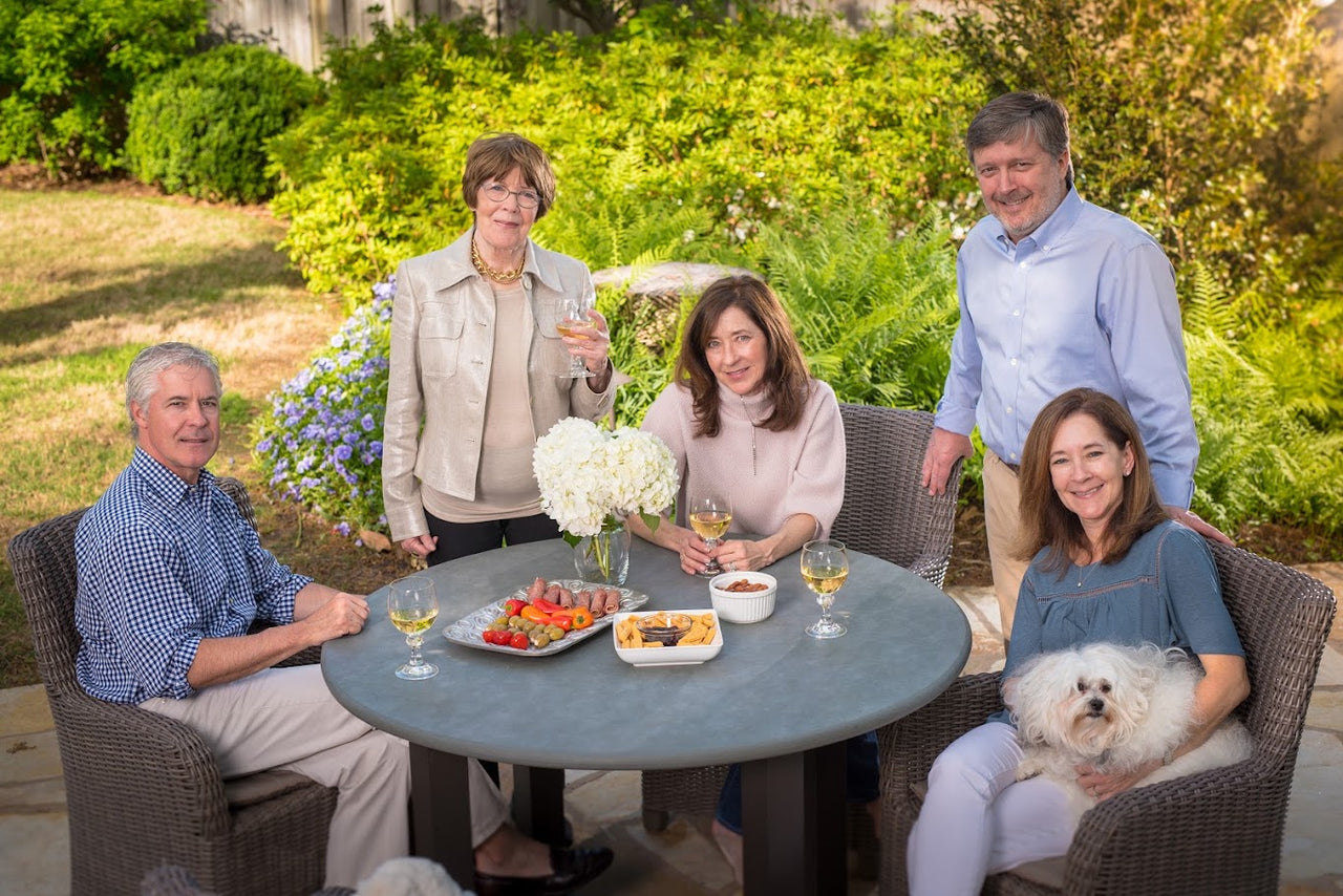 Three generations of the Janis & Melanie family gathered together at a patio table with cheese straws and wine, celebrating the family recipe that started it all.