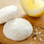 close up image of two Janis & Melanie Lemon Tea Cookies and a wedge of lemon